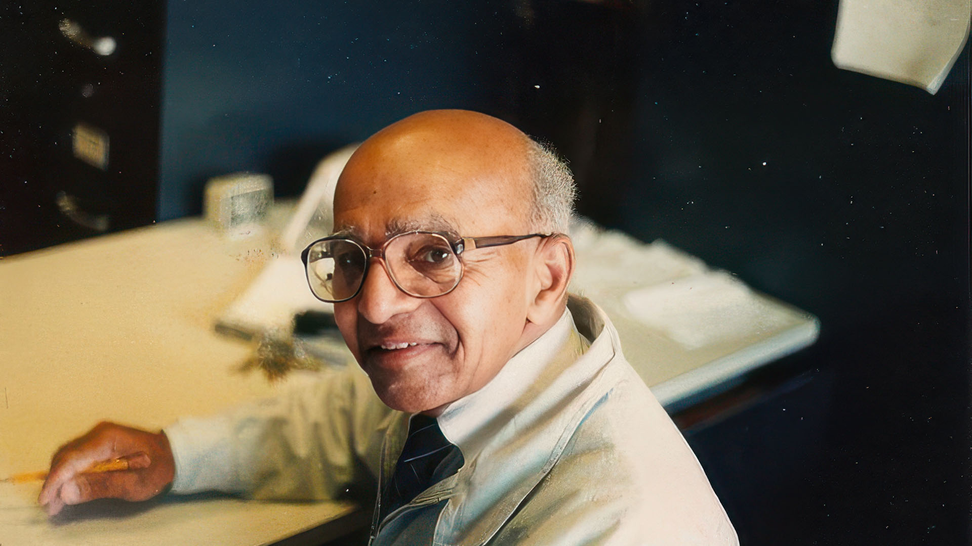 David Blackwell smiling at his desk in his office